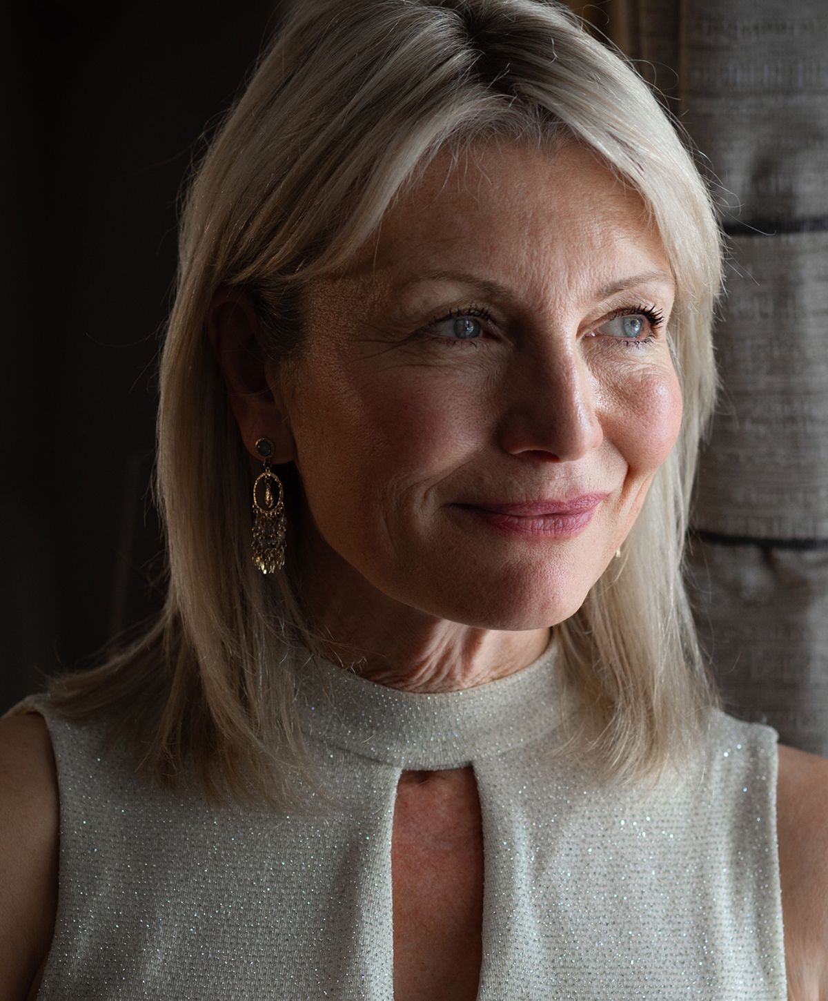 Smiling woman with blonde hair and earrings.