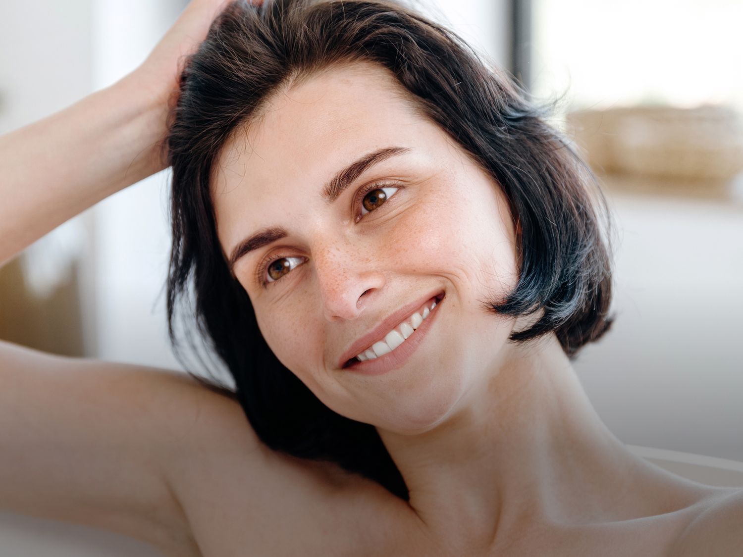Woman touching her face, looking thoughtfully in mirror.
