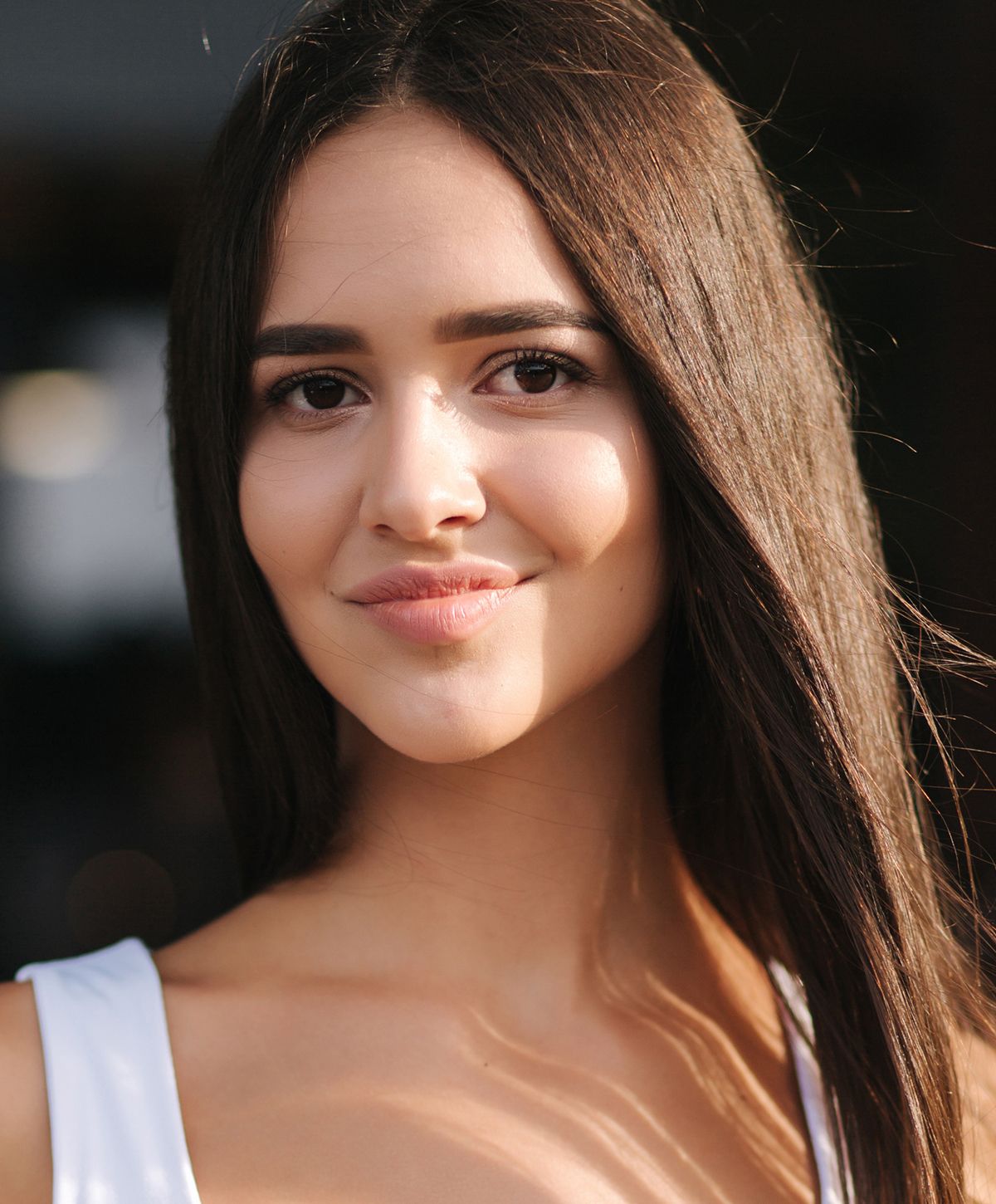 Smiling woman with long, dark hair outdoors.