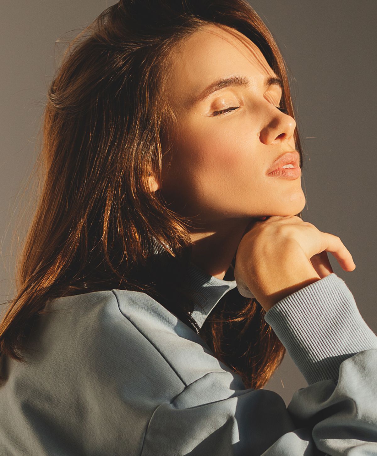 Woman in soft light, eyes closed, thoughtful expression.