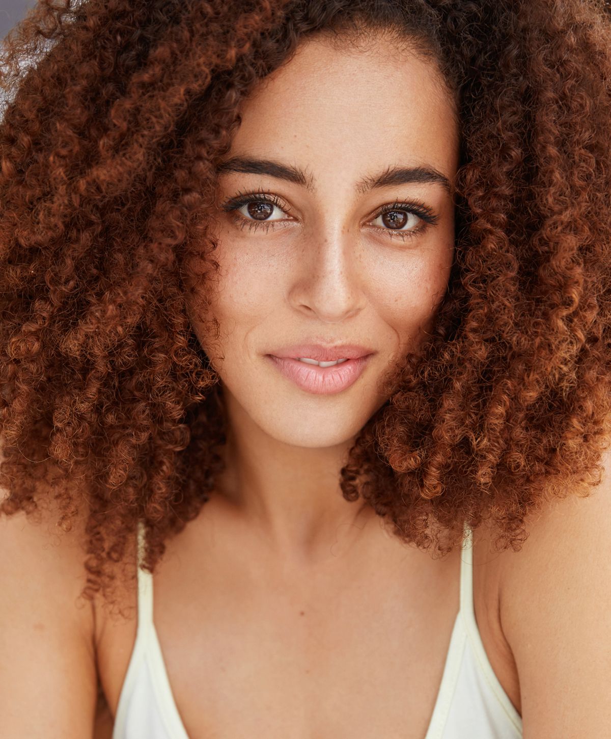 Close-up of a smiling woman with curly hair.