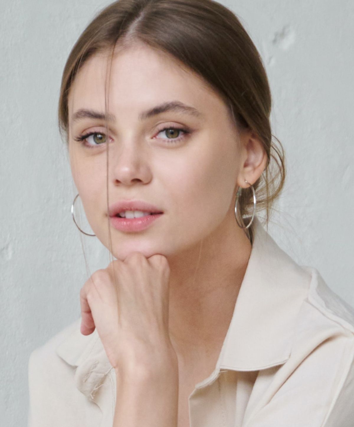 Young woman with light makeup and hoop earrings.