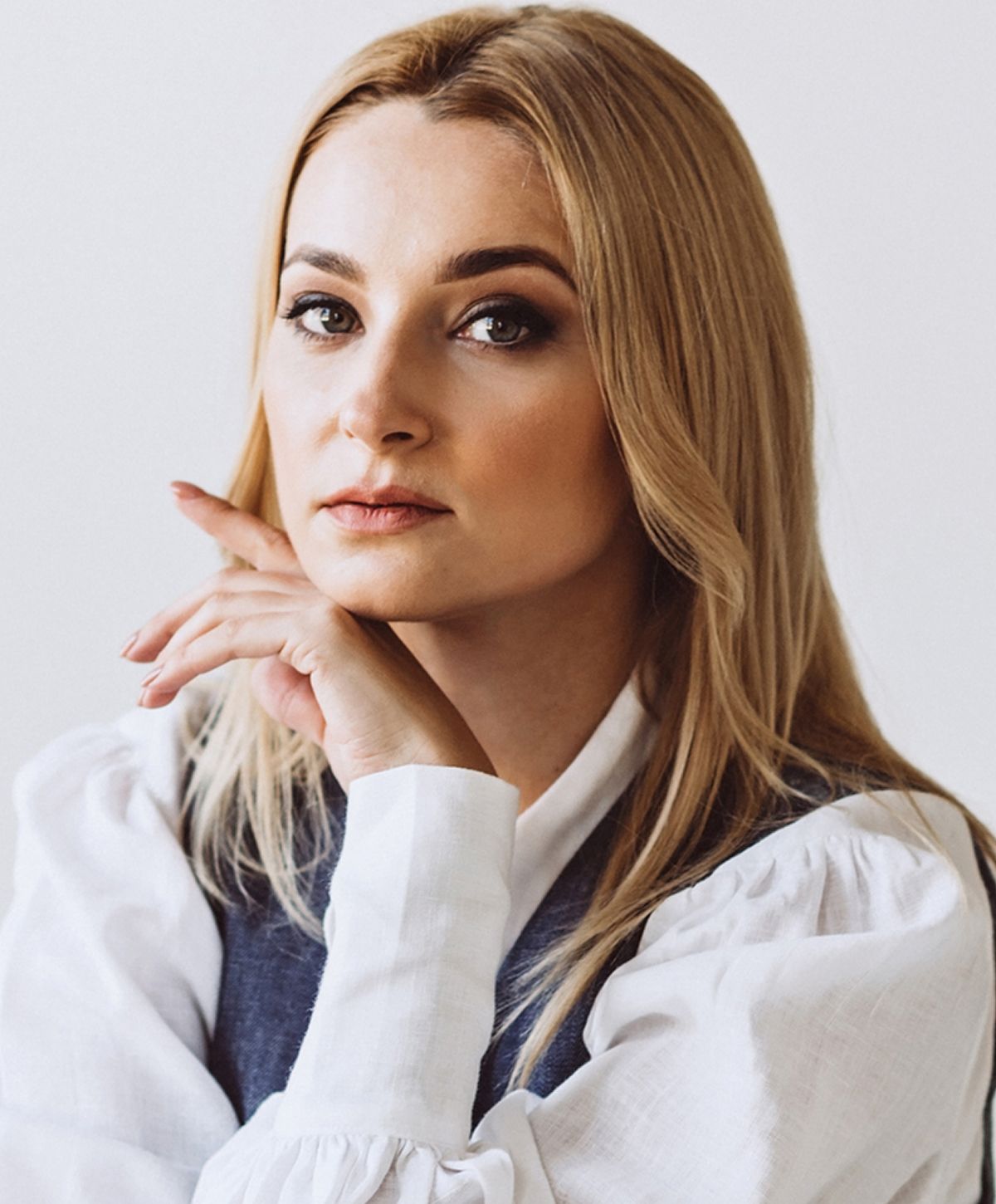 Woman with blonde hair in thoughtful pose.