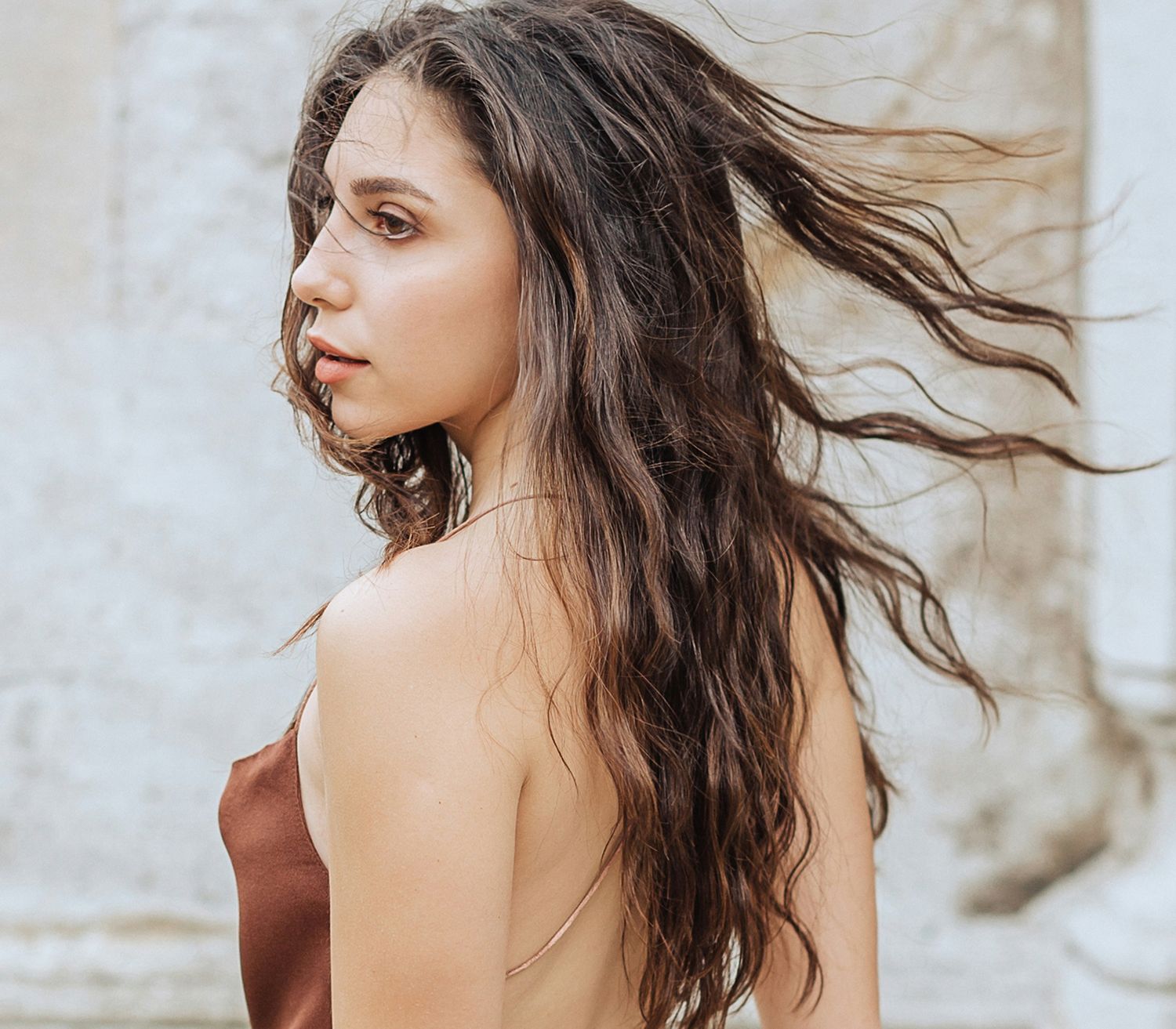 Woman with long, wavy hair looking back.