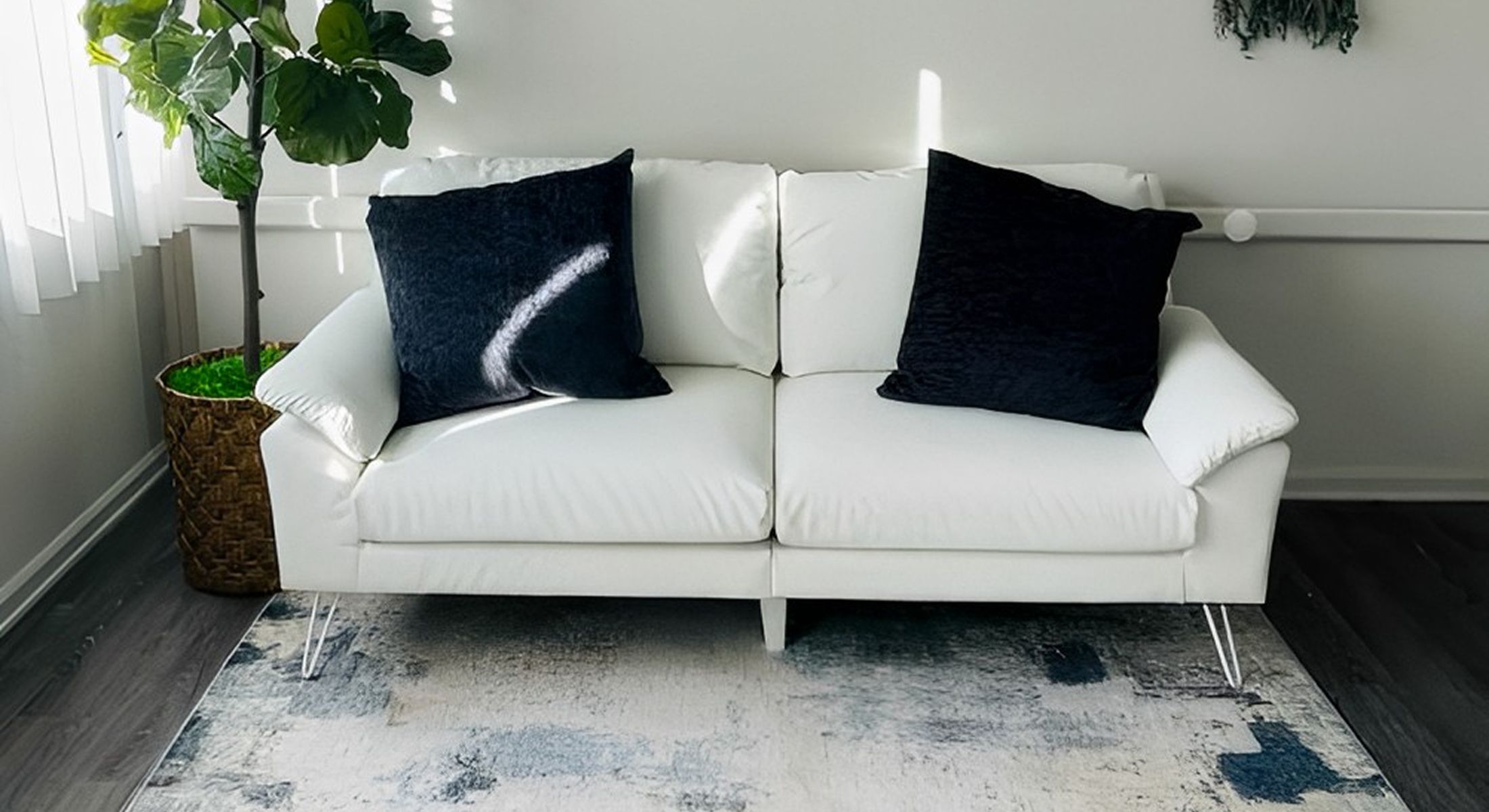 Modern white sofa with decorative pillows and plant.