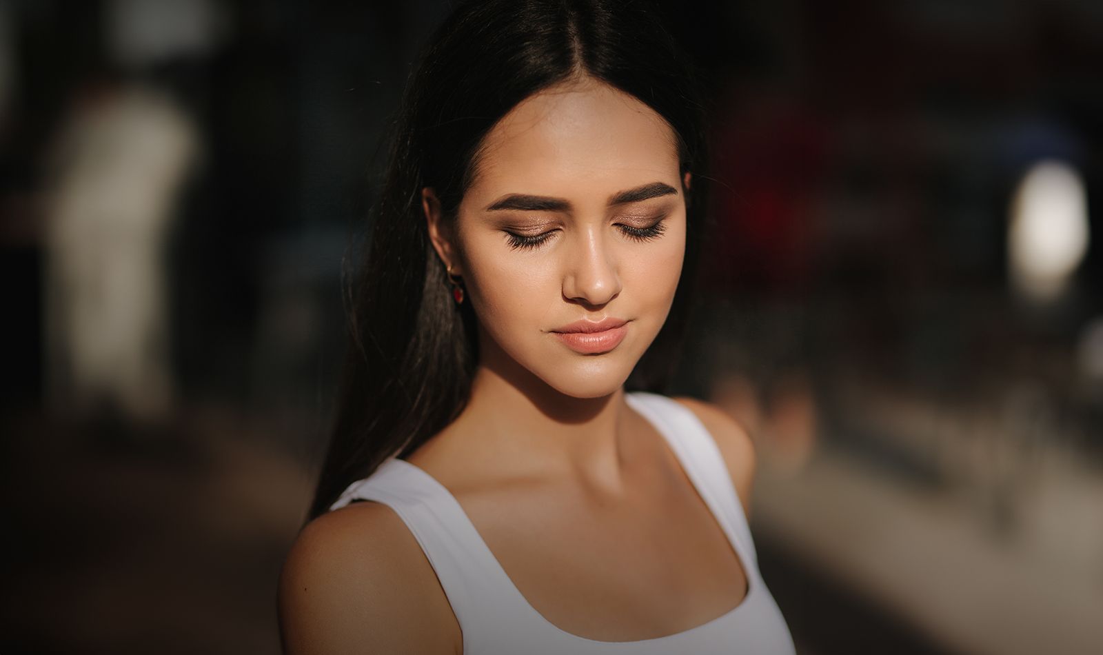 Young woman with closed eyes in soft lighting.