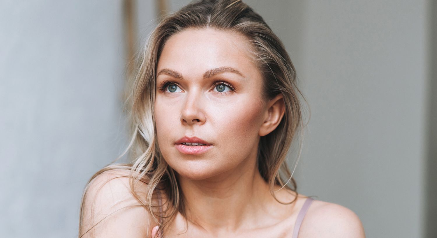 Woman with long hair gazing thoughtfully indoors.