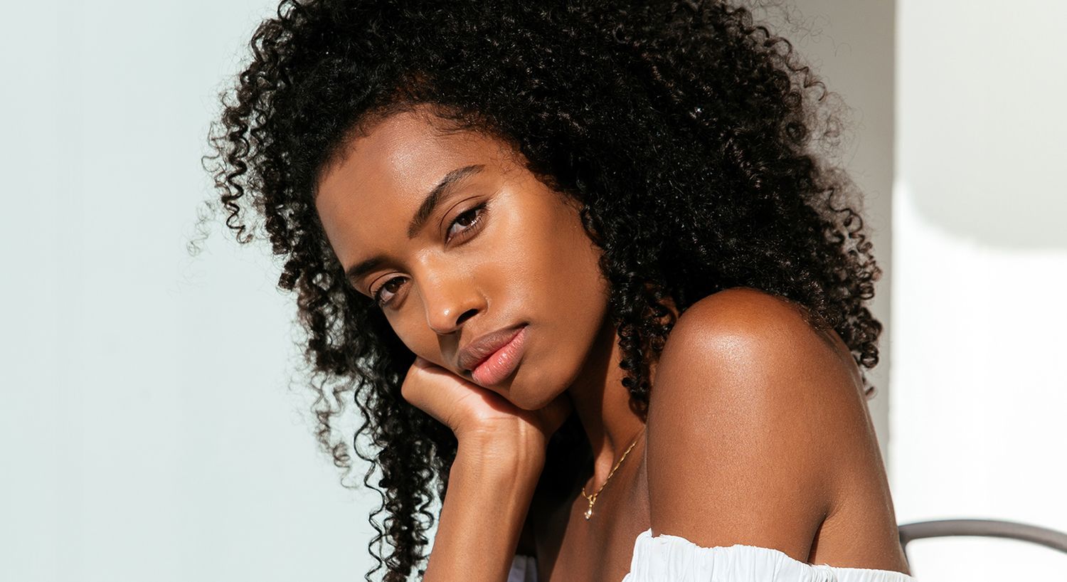 Young woman with curly hair, thoughtful expression.